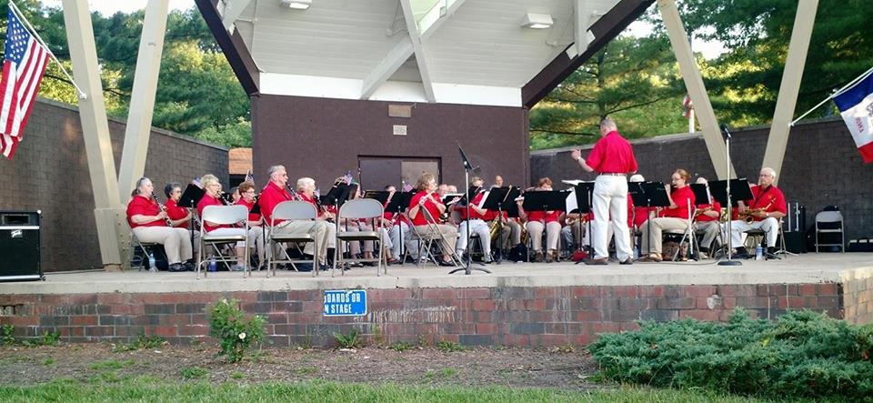 Group of red-shirted musicians playing at the band shell.